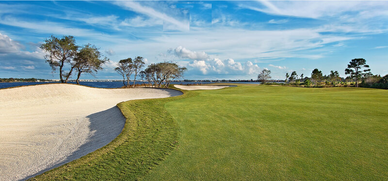 Waterfront golf course with a sweeping fairway and sand bunker